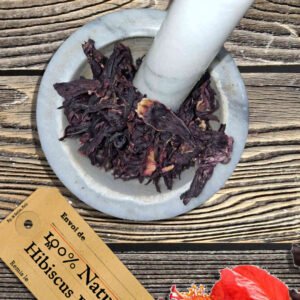 Hibiscus flowers whole in a mortar and pestle with Hibiscus sabdariffa plant - The Herb Peddler