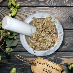 Hops strobiles in a mortar and pestle with Humulus lupulus plant background - The Herb Peddler
