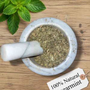 Spearmint dried herb in a mortar and pestle with Mentha spicata plant background - The Herb Peddler
