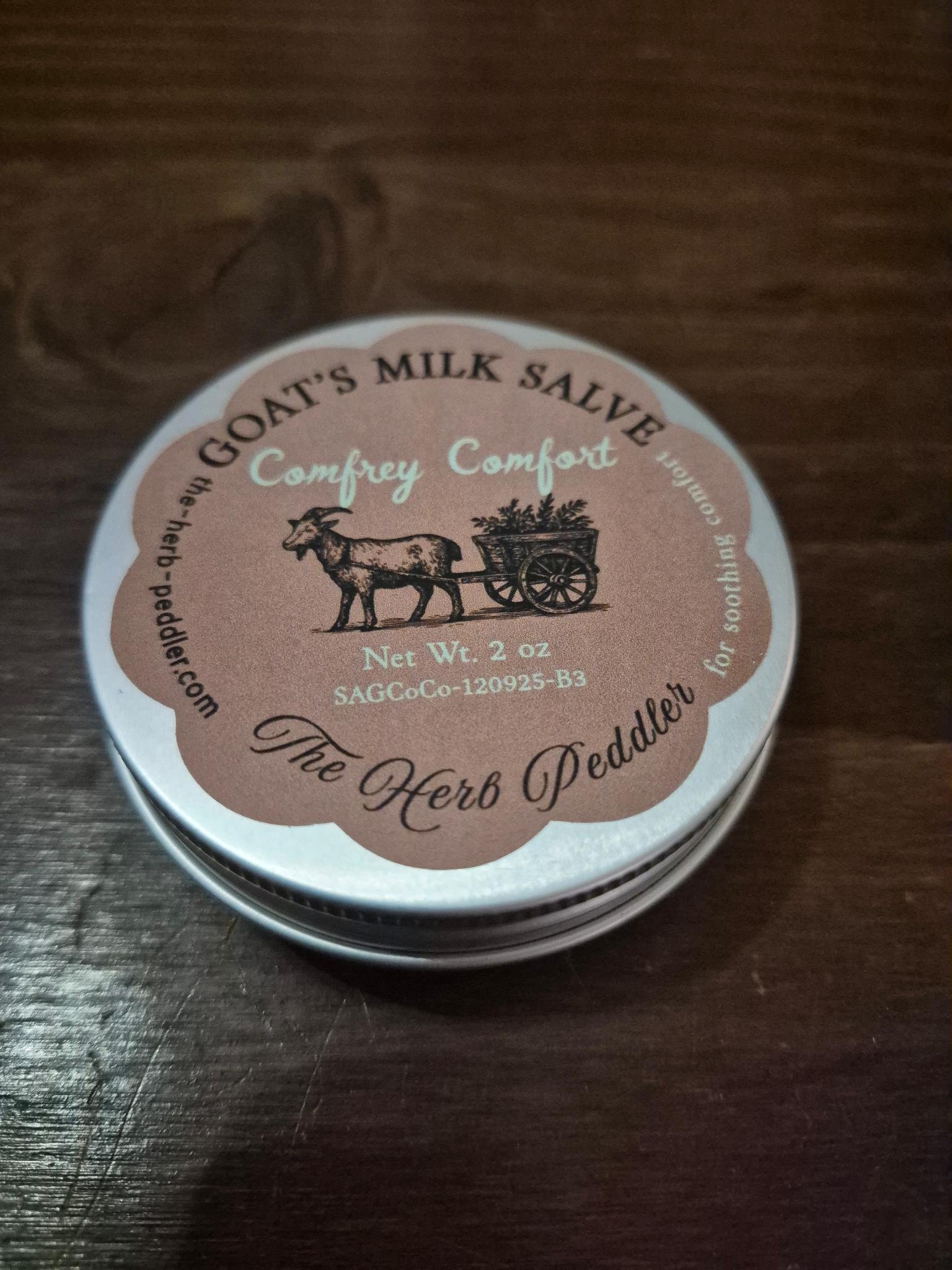 Comfrey Comfort salve in a tin with on old apothecary farmhouse table background - The Herb Peddler