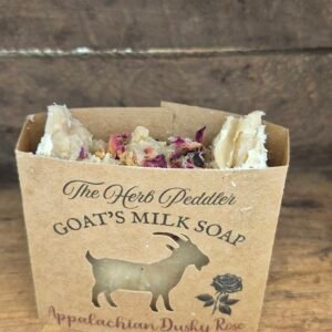 Appalachian Dusky Rose goat milk soap bar with soft pink hues, displayed with dried roses and cedar sprigs against a dusky Appalachian sunset background - The Herb Peddler